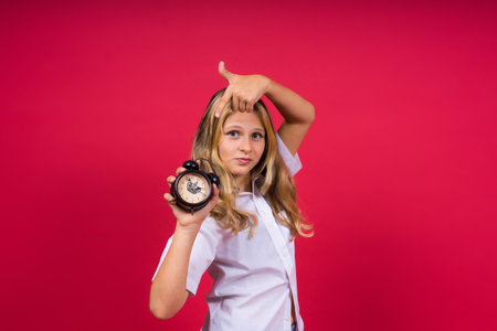 Teen girl 12, 13, 14 years old look at alarm clock. Good morning, checking time. Positive emotions.の写真素材