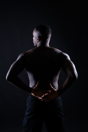 One young african muscular build man standing topless silhouette isolated on black backgroundの写真素材