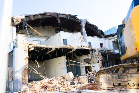 Demolition of the old building with sloopkraan against blue clouds sky.