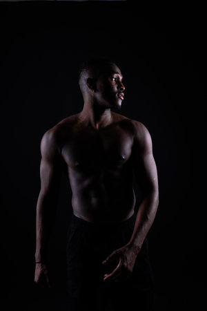Portrait of an athletic african american man topless, black backgroundの写真素材