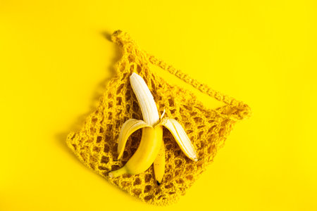 A string bag with bananas isolated on a yellow background.の写真素材