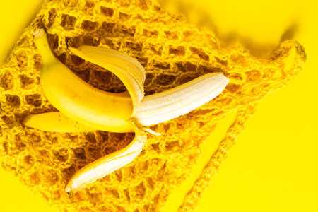 A string bag with bananas isolated on a yellow background.の写真素材