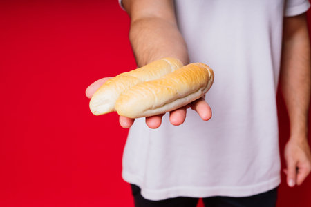 Man with freshly baked bread in the hands isolated on red background studioの写真素材