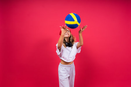 Portrait of a cute eight year old girl in volleyball outfit isolated on red yellow backgroundの写真素材