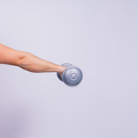 Athletic man doing exercises with dumbbell at biceps on white background. Strength and motivationの写真素材