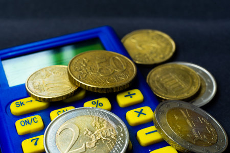 Money concept. Blue calculator with coins euro, close up, dark backgroundの写真素材