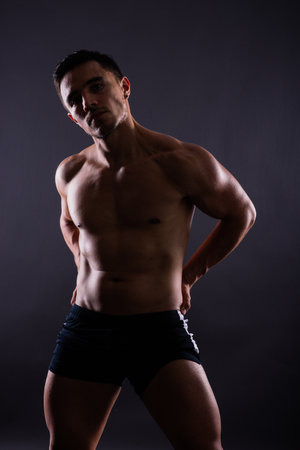 Muscular shirtless young man standing confident, front view, looking at cameraの写真素材