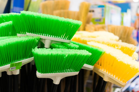 Plastic brushes for cleaning premises. Assortment of multi-colored brooms in the store. Close-up