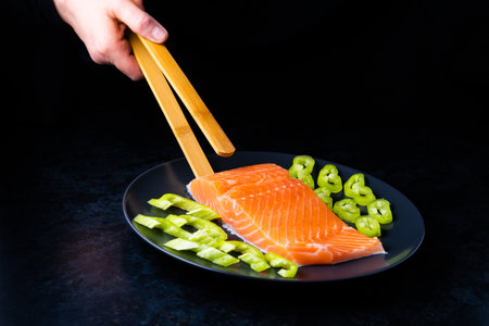 Raw salmon filet with rosemary and spices on plate, black stone background. Top view, flat layの写真素材