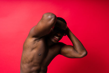 Portrait of an athletic african american man topless smiling, yellow, red and black backgroundの写真素材