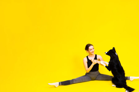 Excited girl dancing with border collie. Studio portrait lady looking at dog with surprised smile.の写真素材