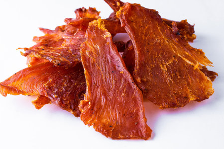 Beef jerky pieces isolated on a white and black backgroundの写真素材