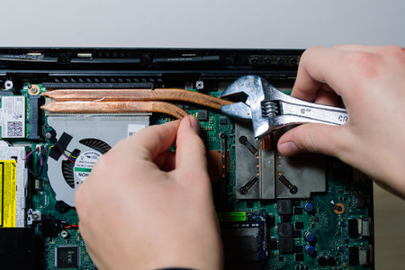 Prague, Czechia - 7th May 2022 Hand technician repairing broken laptop notebook computer with a screwdriverのeditorial素材