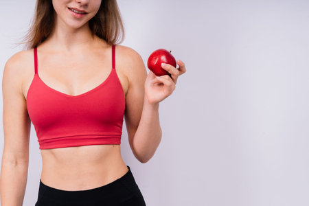 Morning breakfast. Woman with healthy teeth holding apples on grey isolated background.