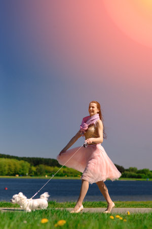 Young woman with her dog. Puppy white dog is running with its owner. Concept about friendship, animal and freedom.の写真素材