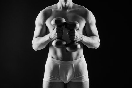Shirtless bodybuilder holding dumbell and showing his muscular arms.の写真素材