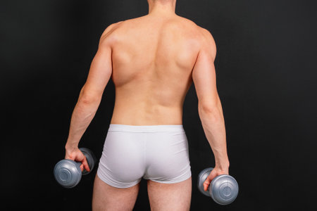 Shirtless bodybuilder holding dumbell and showing his muscular arms.の写真素材