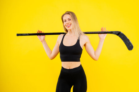 Ice hockey fan female in sports wear with hockey stick in studioの写真素材