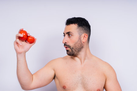 A topless man in jeans with tomatoes in studio, health meal conceptの写真素材