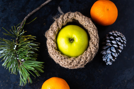 New Year's Christmas still life branch of pine tree next to tangerine cones on black backgroundの写真素材