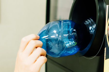 Reverse vending recycling machine that dispenses cash. Man hand puts plastic bottle to machineの写真素材