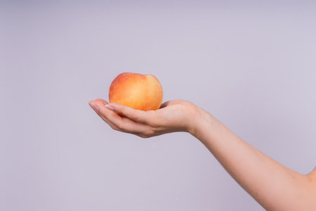 Studio portrait of happy young woman, smiling, holding ripe nectarines in handsの写真素材