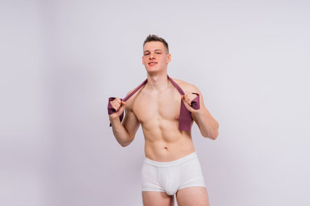 Athlete with a muscular body in white panties is doing physical exercises with rubberの写真素材