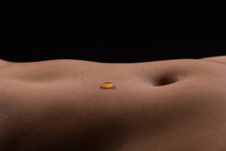 Beautiful female body in honey on dark background, studioの写真素材