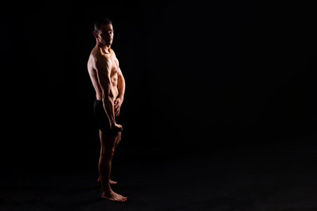 Image of muscle man posing in a studio, dark white red backgroundの写真素材