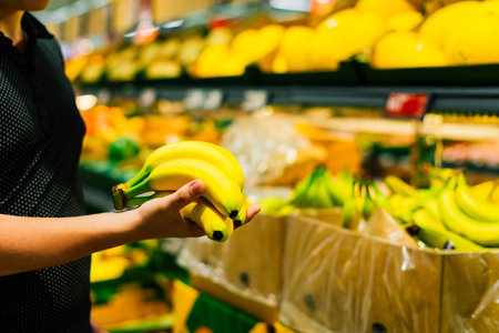 Boy holding a bunch of bananas in the supermarketの写真素材