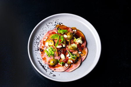 Beef tongue with sauce and vegetables on a white plateの写真素材