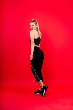 Fit sportswoman in leggings and sports bra looking away and while standing on a yellow redの写真素材