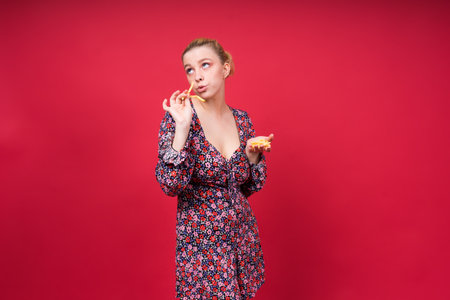 Young beautiful slender female eating a french fries. Concept of unhealthy fat junk and healthy foodの写真素材