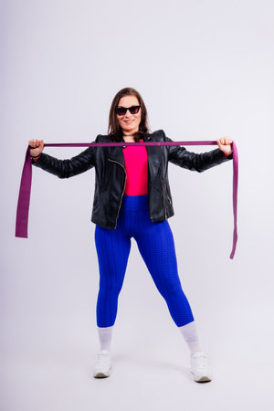 Strong female working with resistance band. Photo of model in fashionable sportswear on grey background.の写真素材