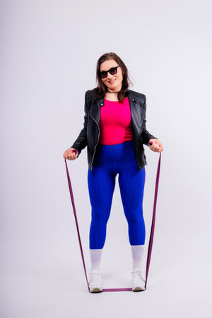 Strong female working with resistance band. Photo of model in fashionable sportswear on grey background.の写真素材