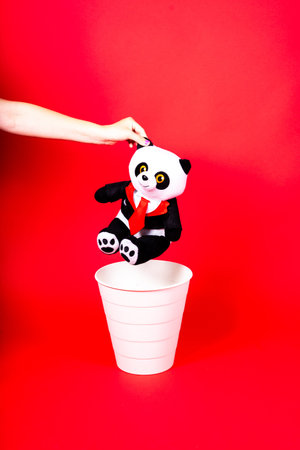 Woman putting the broken toys in waste bin on red background, copy spaceの写真素材
