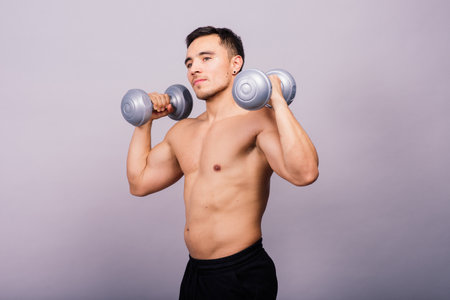 Bodybuilder showing his body and holding dumbells.の写真素材