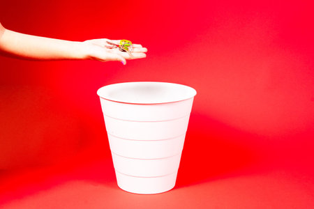 A hand is about to throw a bunch of keys into the trash can.の写真素材