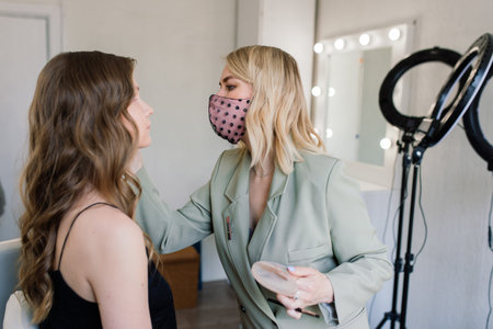 Woman make-up artist work in a studio with model