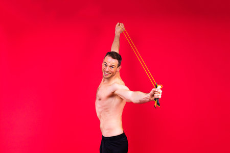 Full length portrait of a young man exercising with a skipping rope and looking at cameraの写真素材