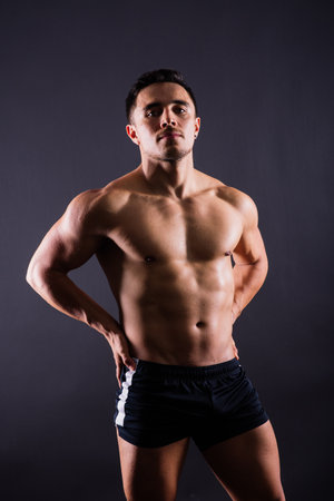 Muscular shirtless young man standing confident, front view, looking at a cameraの写真素材