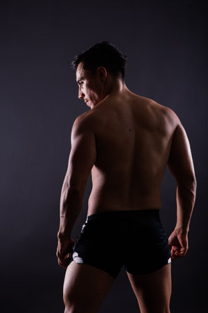Muscular shirtless young man standing confident, front view, looking at a cameraの写真素材