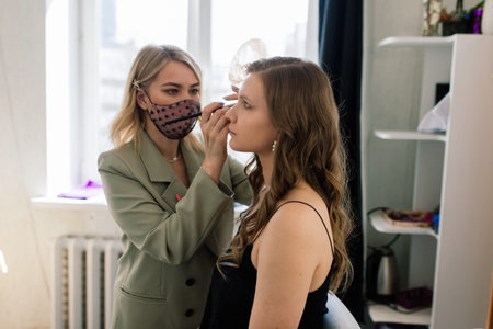 Makeup artist applies lipstick. Hand of make-up master, painting lips of a young beauty model.