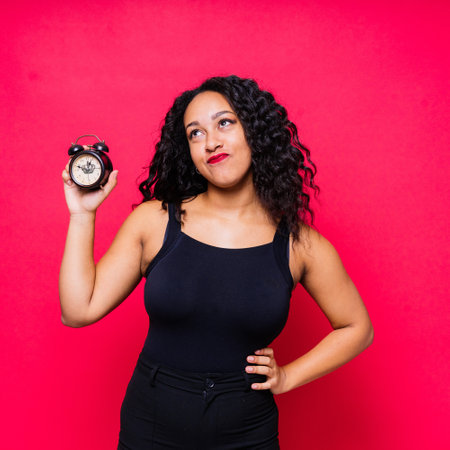 Shocked young woman holding alarm clock, emotional african american female student late to studyの写真素材