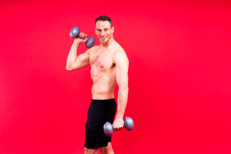 Adult muscular man smiling while working out hard with dumbbells.の写真素材