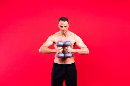 Adult muscular man smiling while working out hard with dumbbells.の写真素材