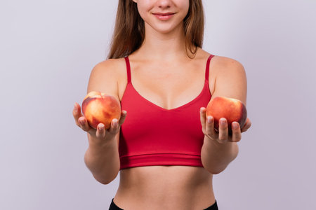 Happy cheerful a young blond woman holding nectarines in handsの写真素材