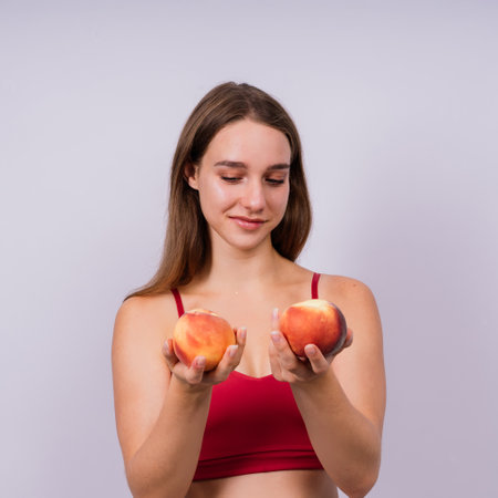 Happy cheerful a young blond woman holding nectarines in handsの写真素材