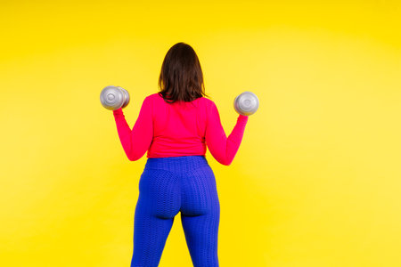 Sporty model with curvy figure with a dumbbells. Dynamic movement. Motivation and healthy lifestyleの写真素材