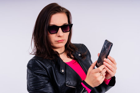Portrait of pretty sad woman holding smartphone with broken screenの写真素材
